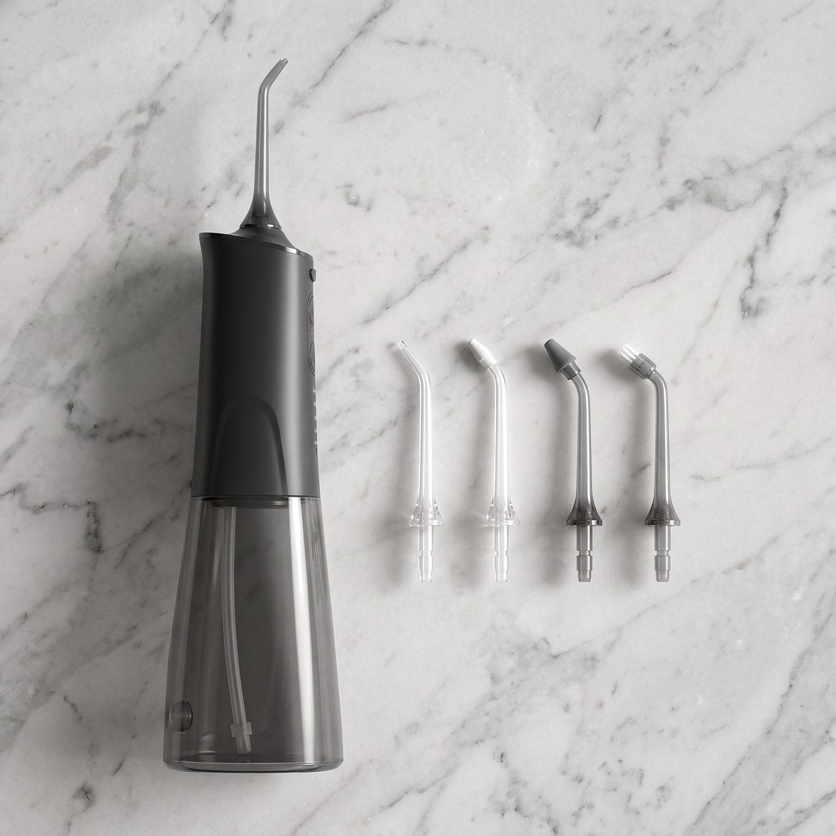 Hydropulseur noir et ses 4 embouts sur un plan en marbre
